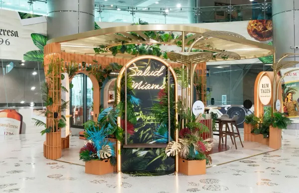 A modern, circular promotional stand for spiced rum inside a brightly lit airport terminal.